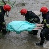 Strażacy wydobywają z rzeki zwłoki kobiety.