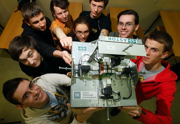 Młodzi robotycy ze swoim robotem układającym kostkę Rubika.