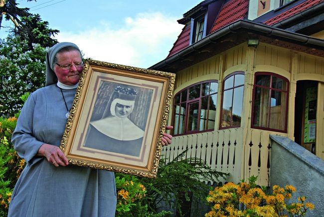  Siostra Paulina, która pracowała nad przygotowaniem izby pamięci, ze zdjęciem Dulcissimy.  W tle klasztor w Brzeziu, w którym Dulcissima mieszkała