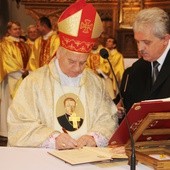 Bp Tadeusz Rakoczy podpisuje wniosek władz samorządowych o nadanie patronatu