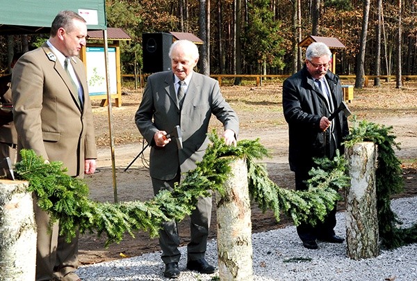  Otwierając ścieżkę, toporkami przecięto symboliczną przegrodę sporządzoną z leśnego igliwia. Pierwszy z lewej Tomasz Sot, dyrektor Regionalnej Dyrekcji Lasów Państwowych w Radomiu 