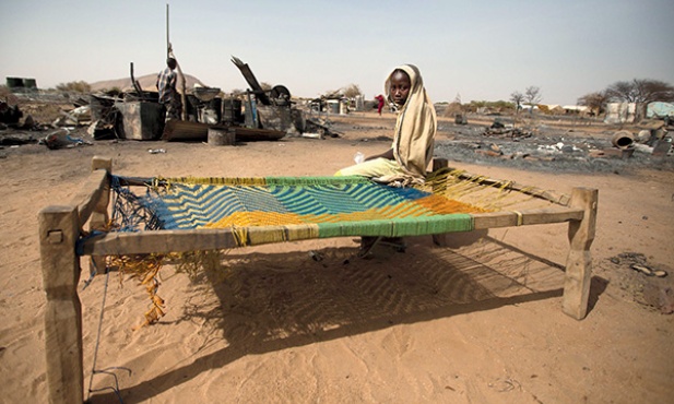  6.04.2014. Sudan. Dziewczyna siedzi na łóżku obok zgliszcz swego spalonego domu. Ponad 3 tys. mieszkańców Darfuru musiało opuścić swoje domy 22 marca br. po ataku zbrojnej grupy