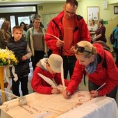 Katarzyna i Jan Kozieł z synem Konradem podpisują się gęsim piórem na dokumencie upamiętniającym skoczowską grę miejską