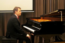 Piotr Latoszyński przy fortepianie w pałacowej sali koncertowej