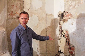 Piotr Jabłoński, konserwator dzieł sztuki i wykonawca prac, wskazuje odkryte polichromie. W tym miejscu postać świętego 