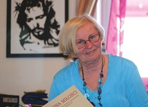 Janina Kowalska-Słysz  trzyma w ręce książkę  o służebnicy Bożej  Marii Epstein 