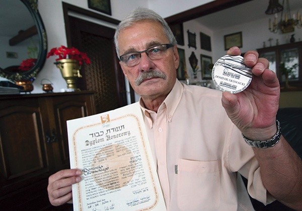 Andrzej Głowacki pokazuje dyplom i medal Sprawiedliwy wśród Narodów Świata przyznany jego ojcu