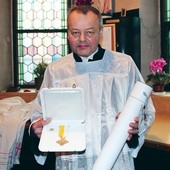 Józef Wloka ze złotym krzyżem w kształcie karo i potwierdzającym jego przyznanie dokumentem 