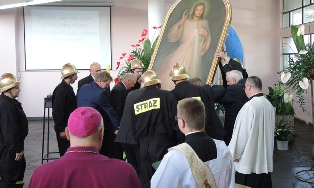 Mężczyźni, w tym grupa strażaków parafii, wnieśli do kościoła obraz Jezusa Miłosiernego
