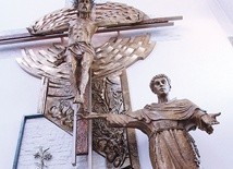 Św. Antoni wskazuje zarazem na ołtarz i na krzyż.  Pod tą kompozycją stoi chrzcielnica.