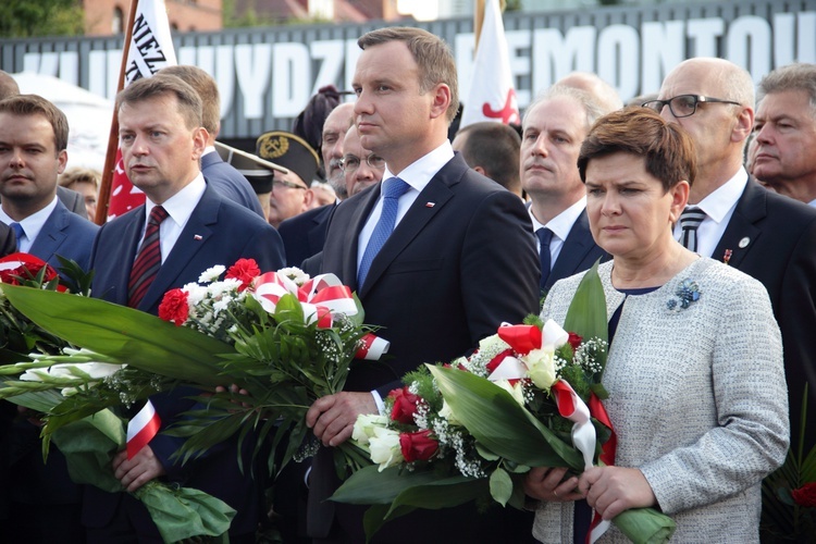 A. Duda i B. Szydło składają kwiaty pod bramą nr 2