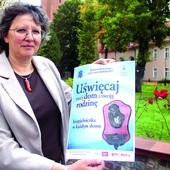 	Joanna Olbert, prezes DIAK AG, prezentuje plakat promujący inicjatywę „Uświęcaj swój dom i swoją rodzinę”.