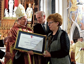 Nagrodę „Viventi Caritate” za rok 2016 z rąk bp. Henryka Tomasika odbiera Lucyna Wiśniewska. W środku Zbigniew Miazga.