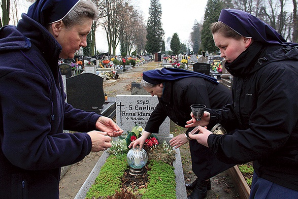 Od lewej: s. Dolores Zok, s. Renata Sałamacha i s. Marta Poświatowska zapalają znicz na grobie s. Caeliany.