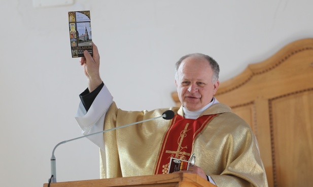 Ks. proboszcz Józef Sowiński zachęca pielgrzymów do zapoznania się z folderem o historii parafii