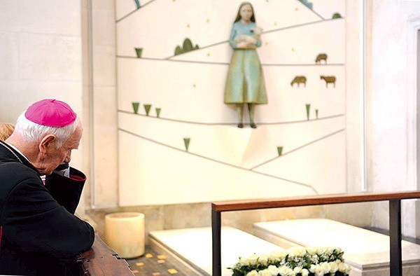 Biskup Ignacy modlący się przy grobie wizjonerów.