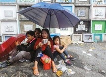 Matka z dziećmi odmawia Różaniec na cmentarzu. 
1.11.2017 Quezon, Filipiny