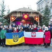 ▲	Pamiątkowe zdjęcie uczestników kolędowania przy szopce ustawionej przed ratuszem.