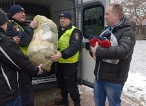 Dary wynoszą strażnicy miejscy. Z prawej ks. Robert Kowalski, szef radomskiej Caritas