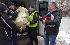 Dary wynoszą strażnicy miejscy. Z prawej ks. Robert Kowalski, szef radomskiej Caritas