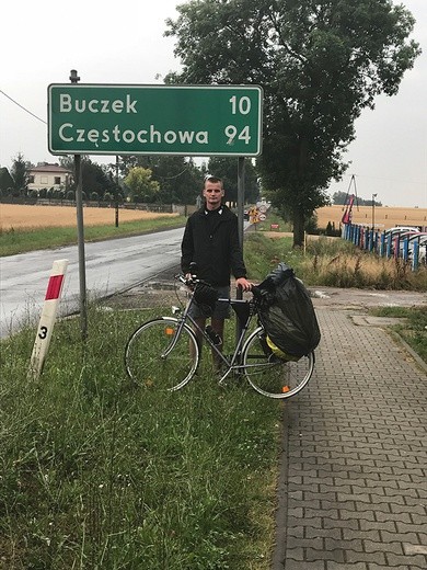 Ksiądz Jakub Kępczyński w Łasku, przy tablicy wskazującej pozostałe kilometry  do Częstochowy.