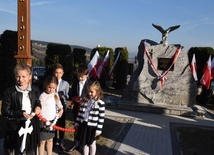 Dzieci z patriotycznym różańcem przed obeliskiem