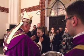 Biskup Zbigniew Kiernikowski podaje kandydatom krzyż  do ucałowania.