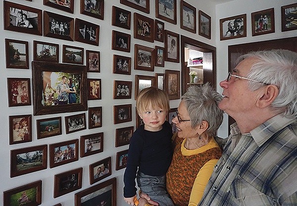 Pani Bożena i pan Ryszard z wnukiem Szymonem oglądają zdjęcia rodzinne wykonane przez córkę Martę.