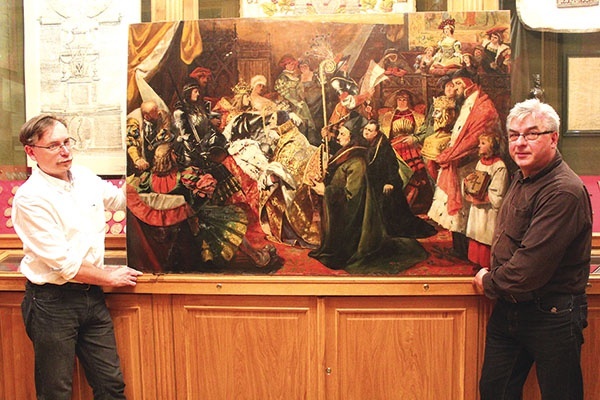 ▲	Ksiądz Andrzej Milewski i Szymon Zaremba, konserwator dzieł sztuki, prezentują odzyskany obraz „Nadanie herbu Kapitule Katedralnej Płockiej”.