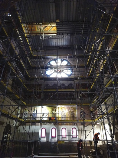▲	Wnętrze odzyskuje historyczny wygląd: południowa ściana transeptu w trakcie transferu wtórnych malowideł, zasłaniających oryginalne anioły. U góry w otworze podestu widać dekoracje stropu po renowacji.