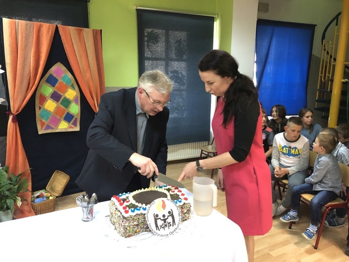 Urodzinowy tort zdobiło logo "Ignis", a kroili: ks. Ignacy Czader i Agnieszka Habrzyk, obecna szefowa świetlicy
