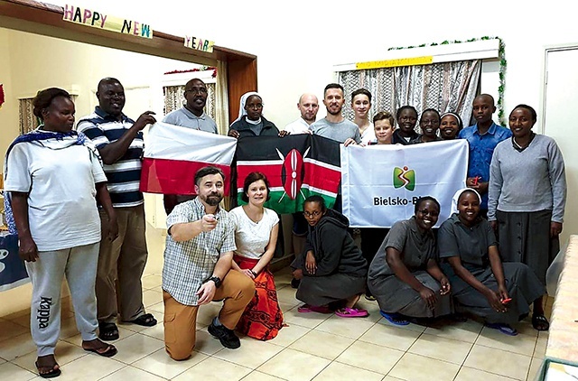 Wolontariusze z flagami polską i kenijską wśród misjonarzy w Kenii.