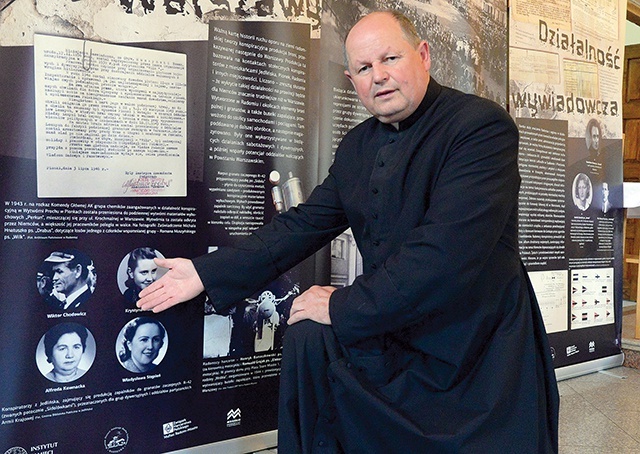 ▲	Ksiądz Krzysztof Chodowicz pokazuje fotografię swego ojca, umieszczoną na jednej z tablic wystawy IPN.