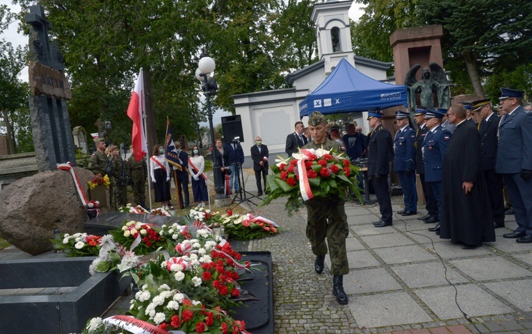 Kwiaty przy pomniku katyńskim składają przedstawiciele służb mundurowych.