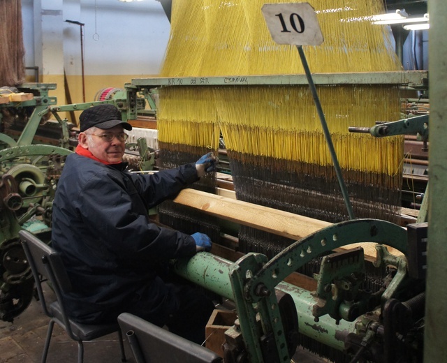 Marek Wójcicki czuwa nad zamontowaniem żakardów nad krosnami. Część z nich wytwarza już próbki materiałów.