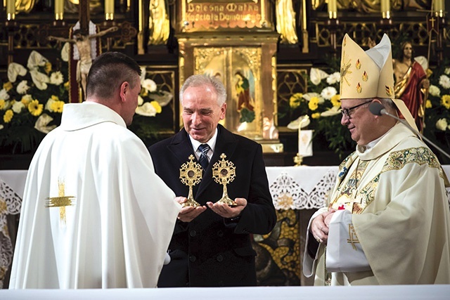 ▲	Prowincjał w obecności biskupa wręcza relikwiarze dr. Jerzemu Miszkiewiczowi, prezesowi stowarzyszenia.