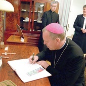 Bp Piotr Turzyński wpisuje się do księgi pamiątkowej klasztoru.