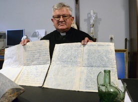 Ks. Andrzej Margas pokazuje dokumenty znalezione podczas prac przy montowaniu instalacji przeciwpożarowej w zabytkowej świątyni.