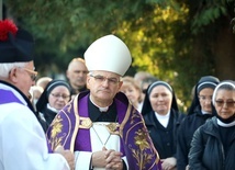 Biskup w czasie procesji z modlitwą różańcową między grobami.