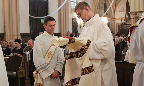 Ks. proboszcz Jan Duraj pomaga nałożyć dalmatykę diakonowi Mateuszowi Kuryle.