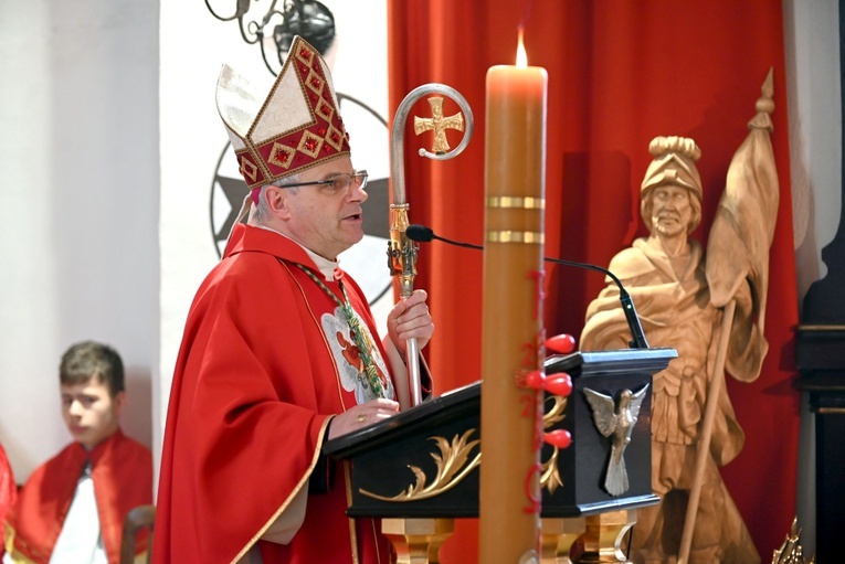 Biskup w czasie głoszenia homilii w kościele parafialnym. W tle rzeźba patrona strażaków.