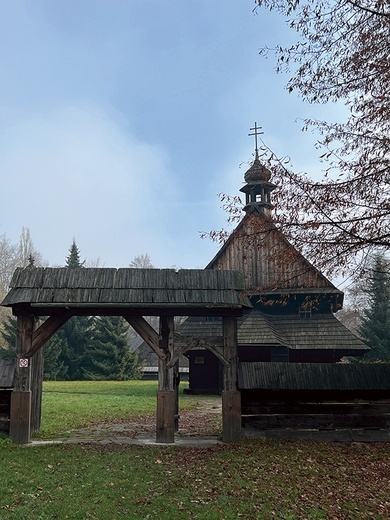 Drewniany budynek  na terenie muzeum wzorem dawnych świątyń otoczony  jest płotem.