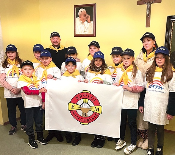 Każdy członek ma koszulkę z symbolem, czapeczkę, żółtą chustę i odznakę z krzyżykiem. Na zdjęciu dzieci z Kątów Wrocławskich z opiekunami.