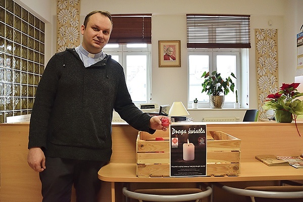 Ks. Andrzej Wiecki prezentuje skrzynkę do woskowego recyklingu.