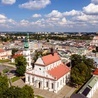 Zamość z lotu ptaka. Na pierwszym planie kolegiata. W tle skąpane w słońcu ulice przecinające się pod kątem prostym.