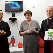 	Bp Marek Solarczyk ze świąteczną kartką, którą dostał od dzieci, obok Bożenna Pacholczak i ks. Krzysztof Andaś.