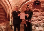 „Książę” (Jarosław Minkiewicz) z Kazimierzem Klawitrem, prezentujący kopię dyplomu we wnętrzu Piwnicy Romańskiej.