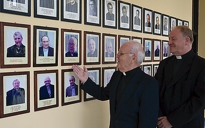 Ks. Jan Skolik i ks. Henryk Jonczyk prezentują galerię dawnych i obecnych mieszkańców domu, która mieści się w holu
