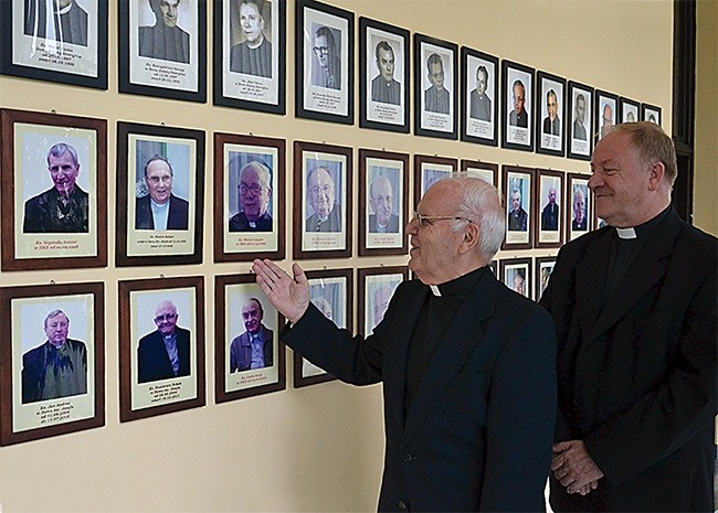 Ks. Jan Skolik i ks. Henryk Jonczyk prezentują galerię dawnych i obecnych mieszkańców domu, która mieści się w holu