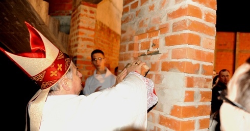 Bp Henryk wmurowuje w ścianę rosnącej świątyni na radomskim Sadkowie cegłę pochodzącą w domu rodzinnego Karola Wojtyły